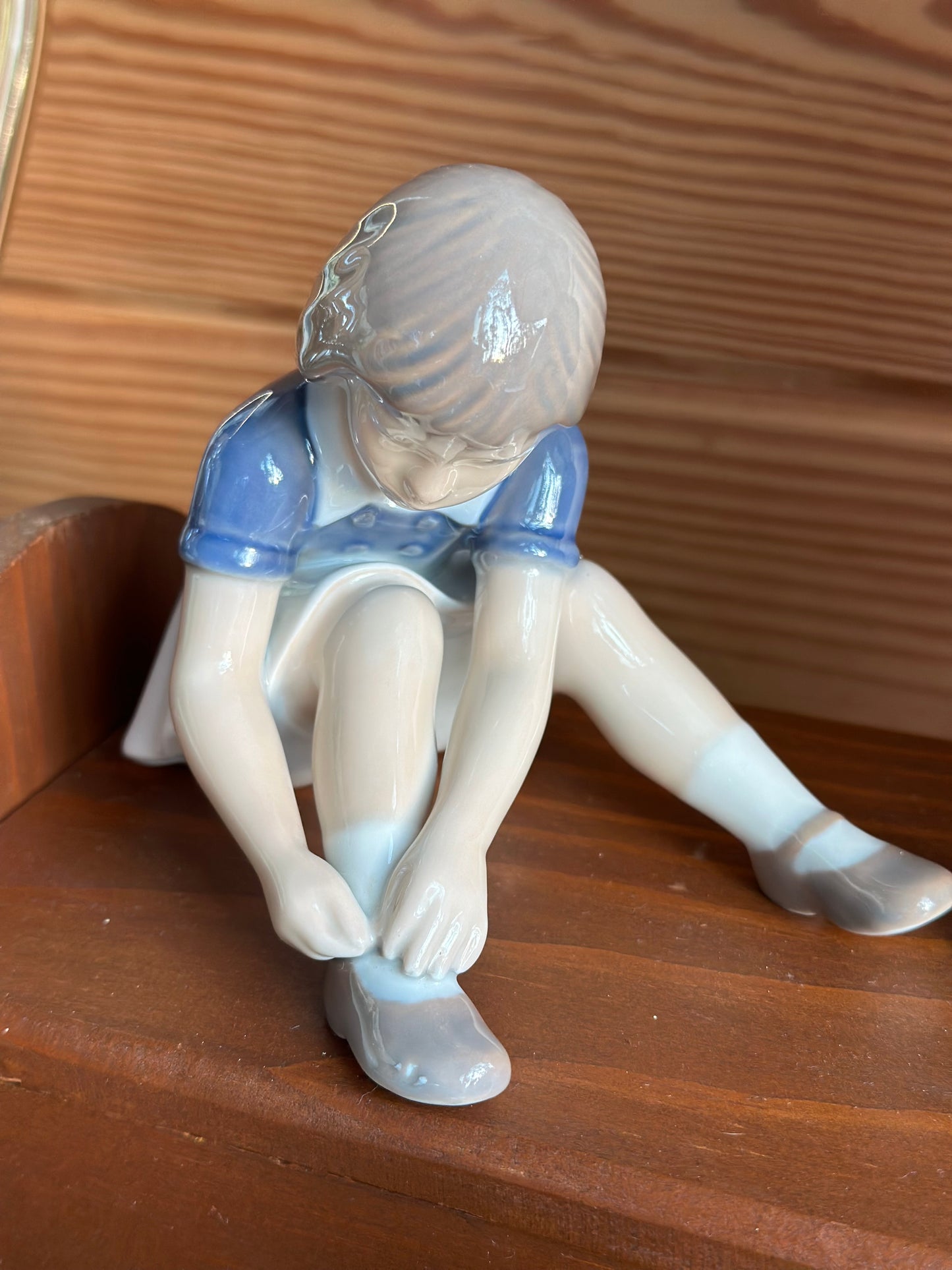Vintage B&G porcelain figurine of a girl buttoning her shoes, featuring soft colors and lifelike details. A charming collectible for home decor.