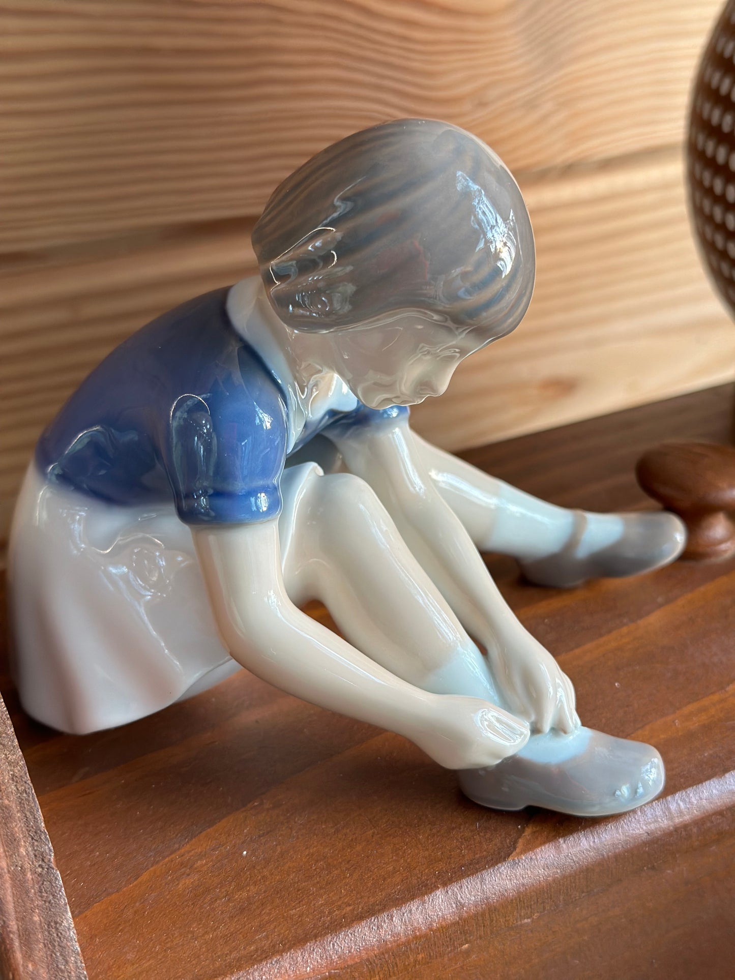 Elegant B&G porcelain figurine depicting a young girl fastening her shoes, crafted with delicate details. A perfect vintage decor piece or gift.