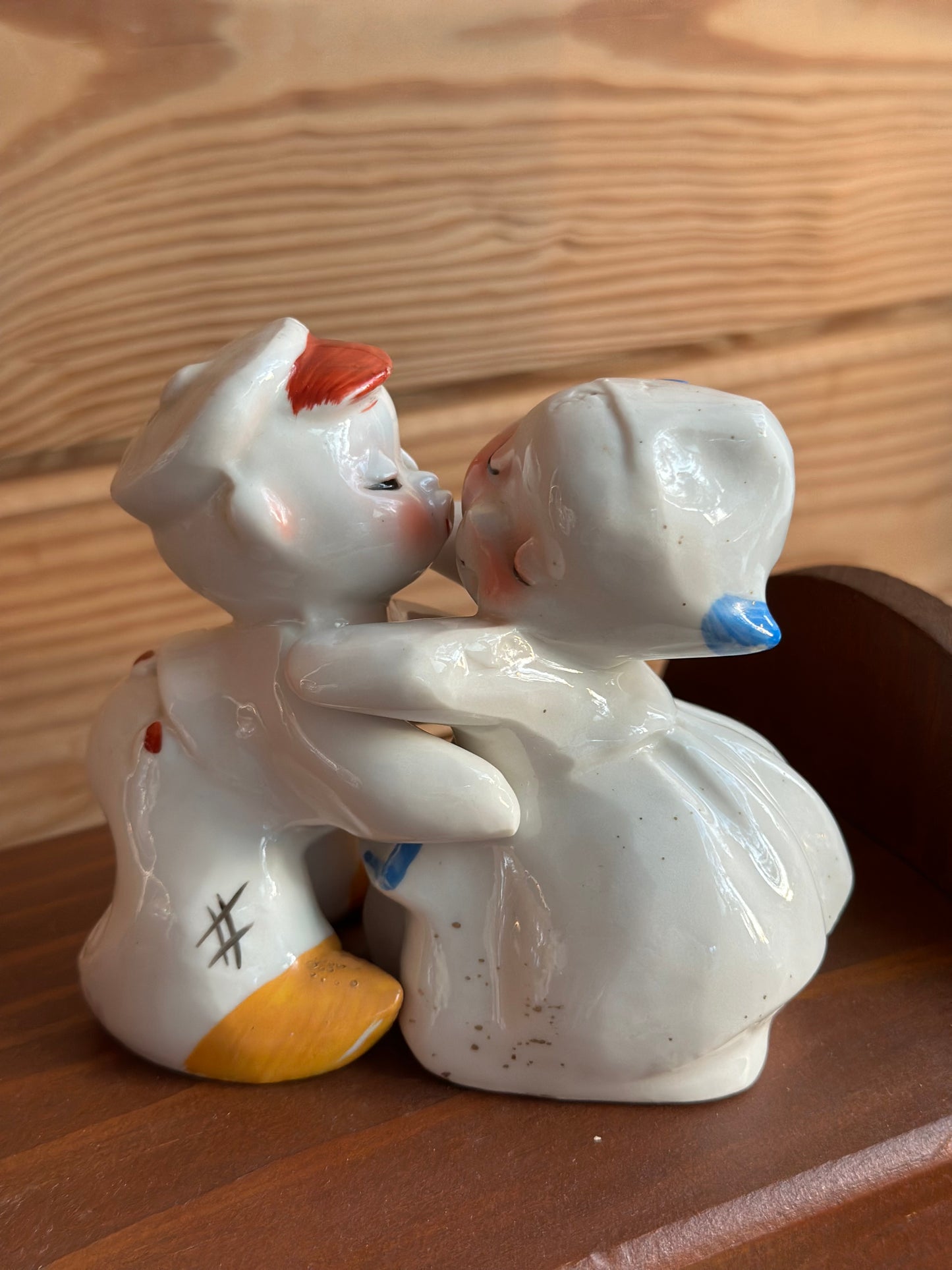 Close-up of ceramic baby boy and girl salt and pepper shakers embracing, showcasing intricate hand-painted details. A whimsical and collectible kitchen accessory.