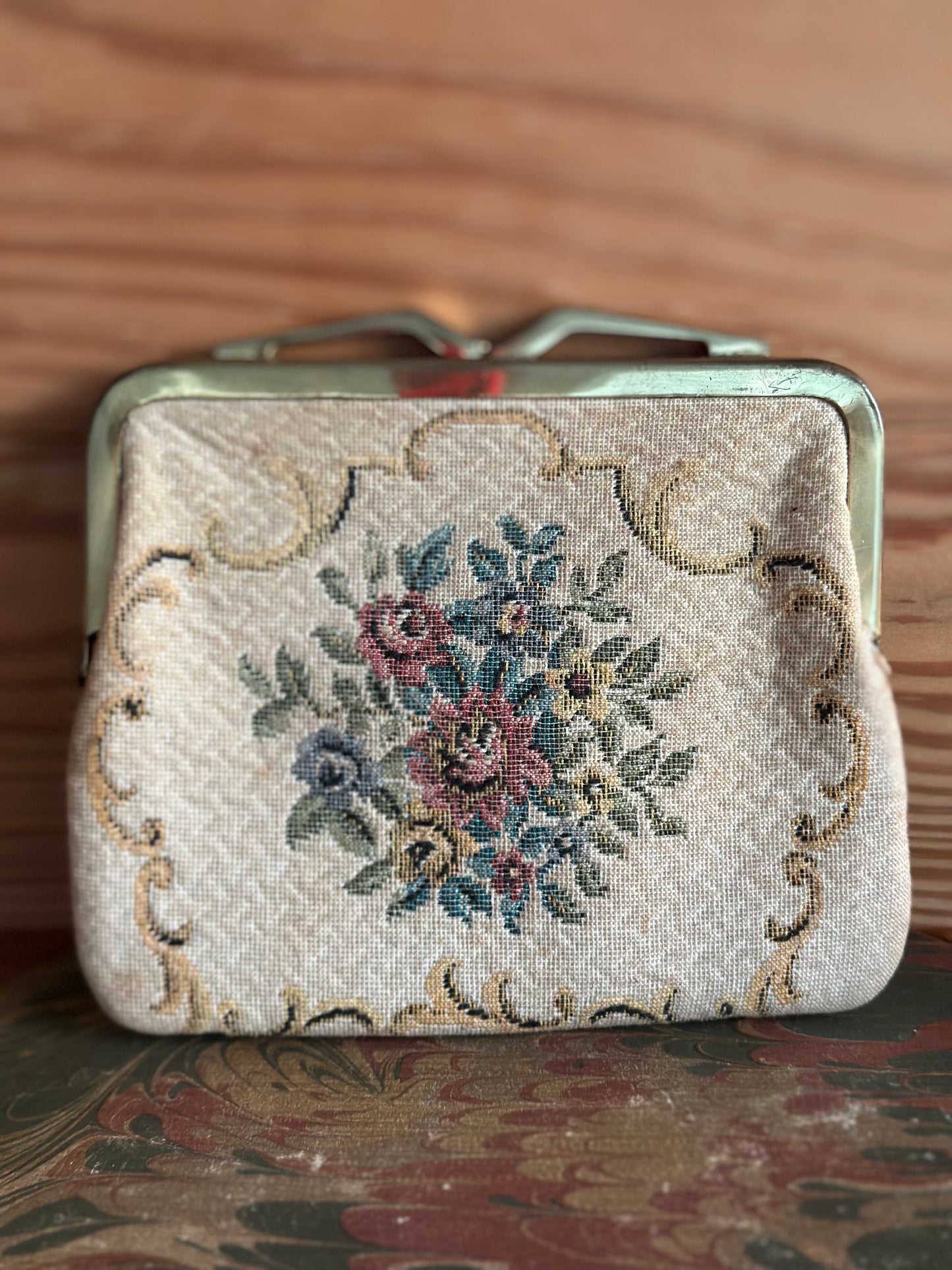 Vintage 1950s Neiman Marcus coin purse with floral tapestry design and brass clasp, featuring intricate embroidery on a cream fabric background.