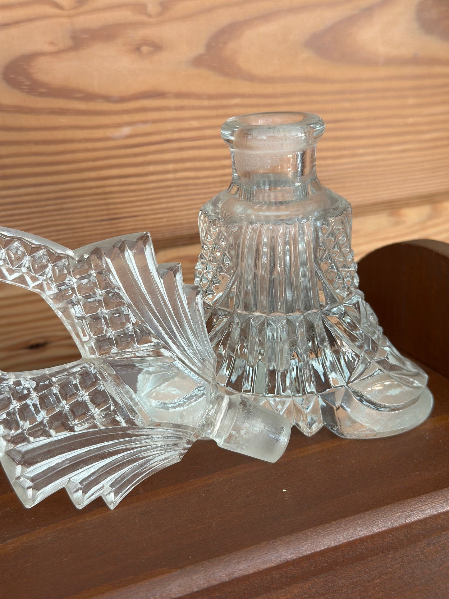 Disassembled vintage clear glass perfume bottle showcasing its ornate stopper and finely crafted base, highlighting exquisite Czech glass artistry.
