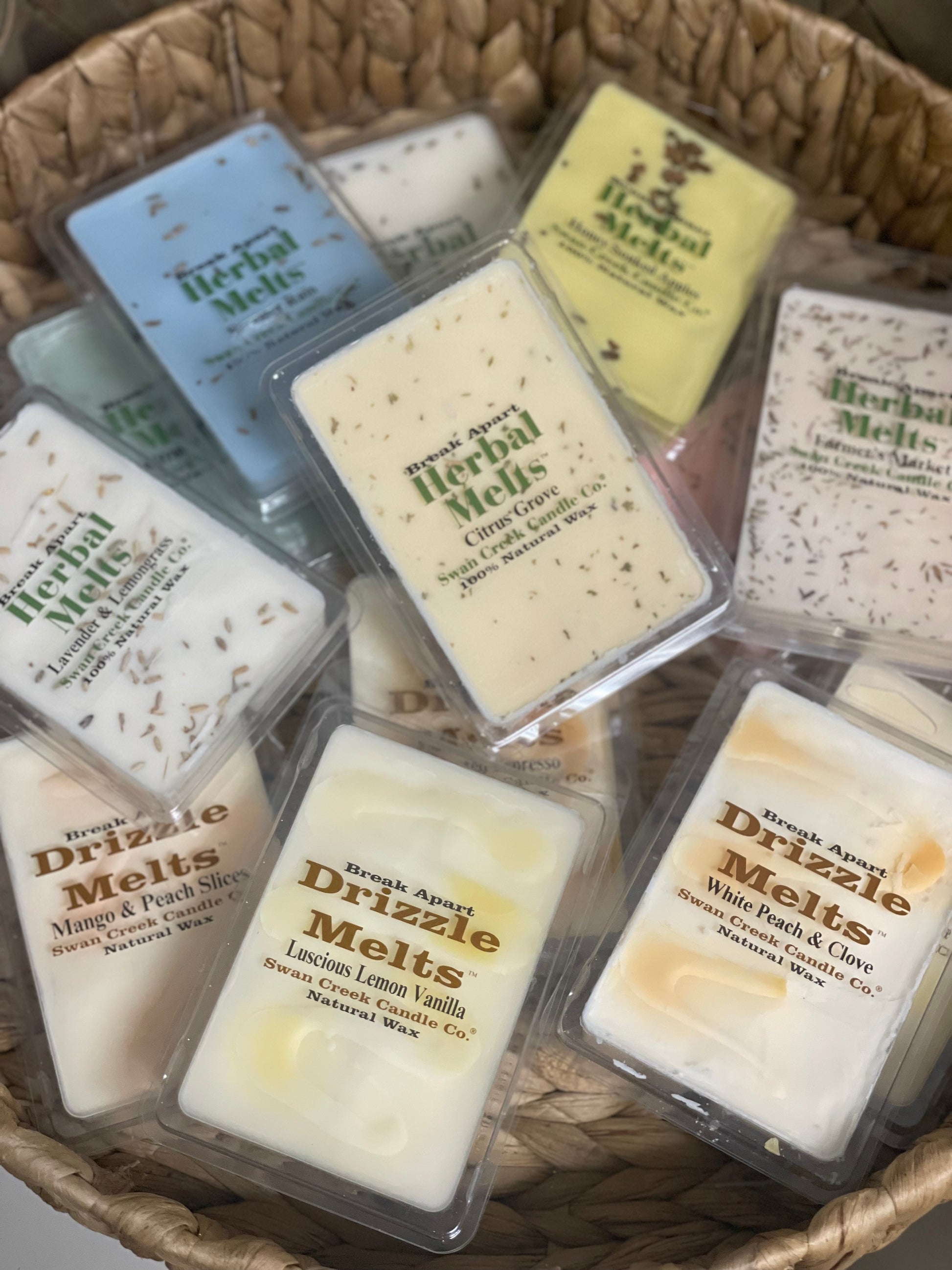 Assorted Swan Creek Herbal Melts candle wax cubes in a woven basket. Scented break-apart wax tarts for home fragrance in various aromas.