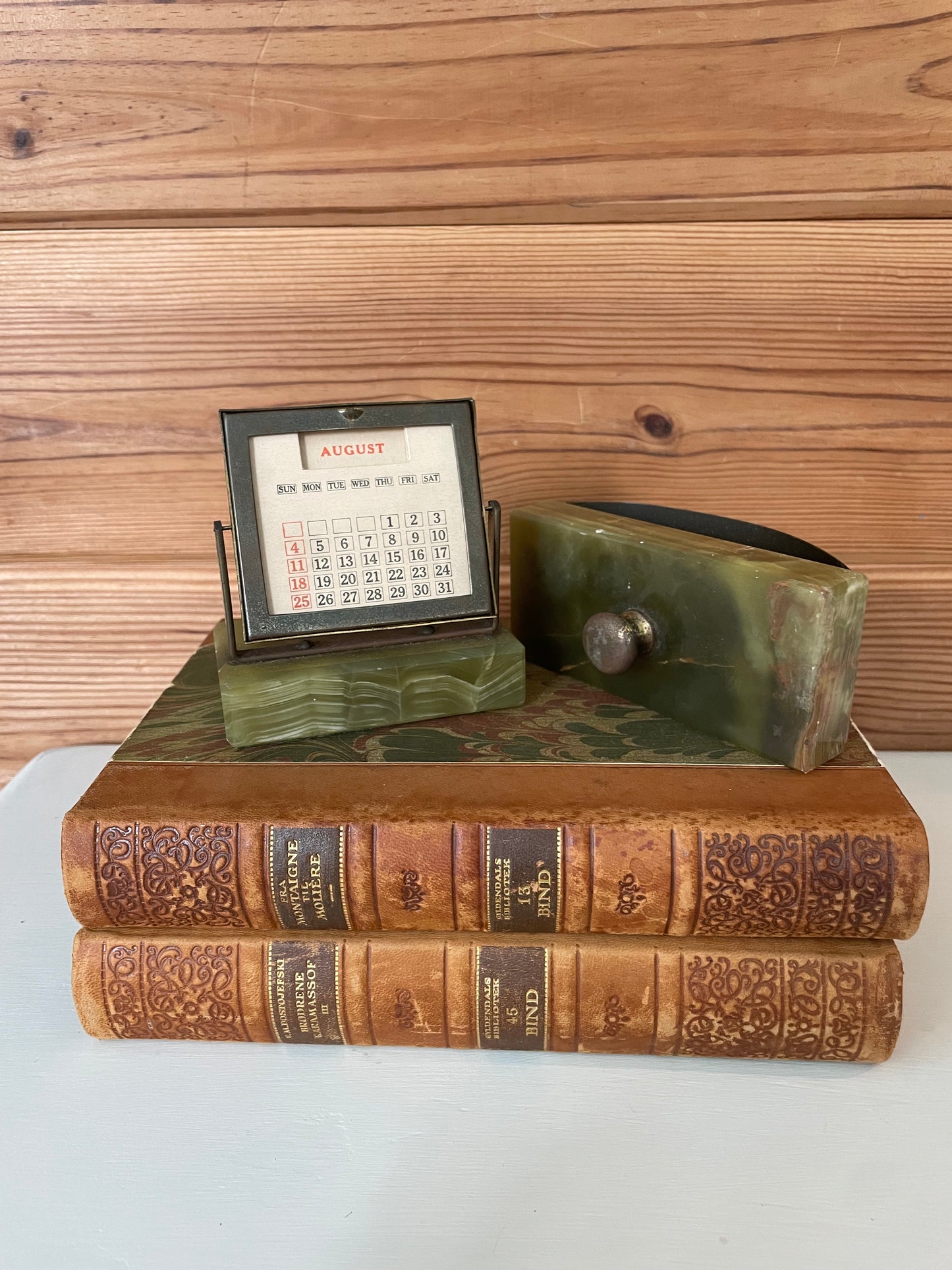 Vintage green marble perpetual calendar and ink blotter set on antique books, adding a classic touch to office decor.