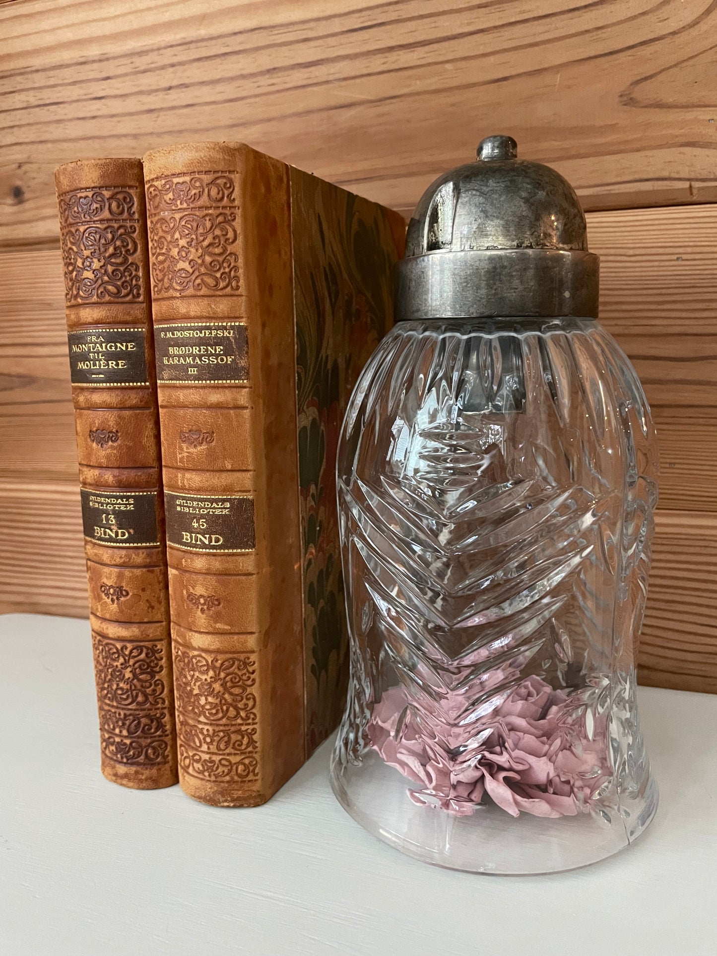 Vintage glass hurricane cloche with intricate cut-glass design and metal top, placed beside antique books. Ideal for home decor or display.