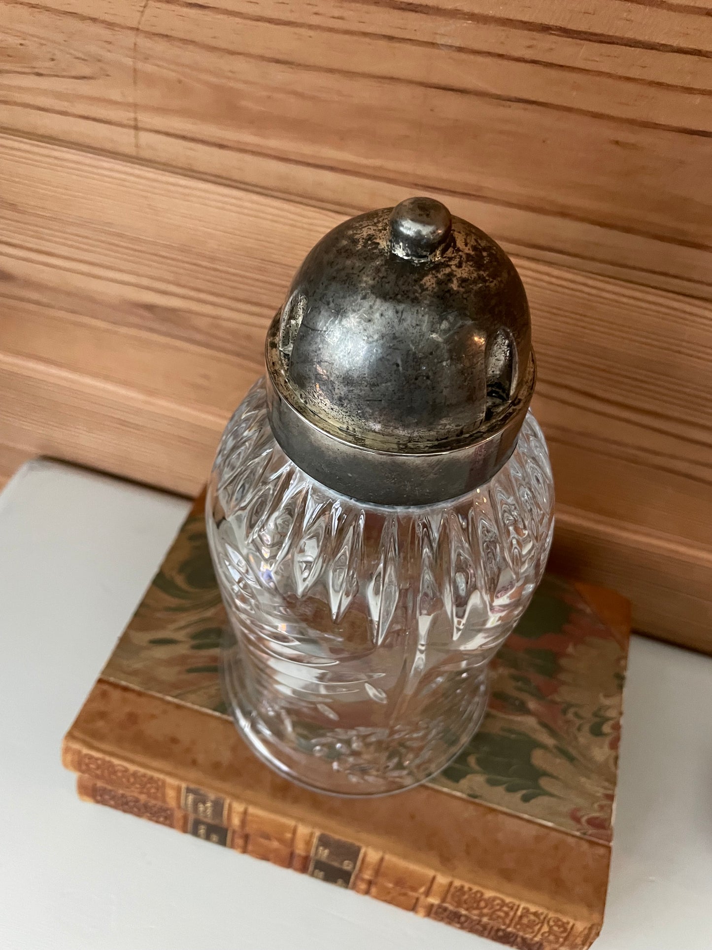 Top view of a vintage glass hurricane cloche with a metal lid, showcasing its intricate cut-glass pattern. A timeless home decor accent.