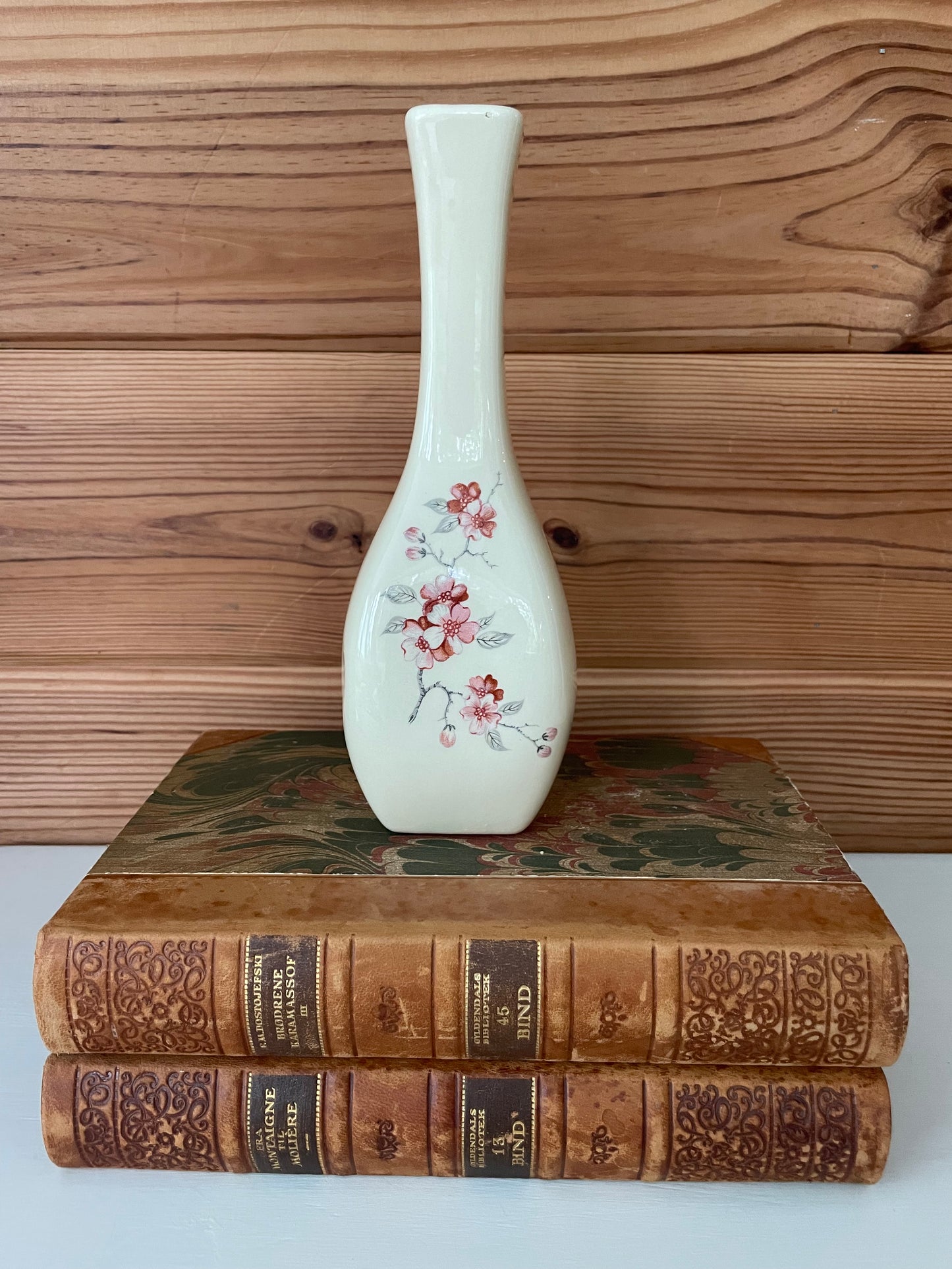 Vintage ceramic cherry blossom bud vase with hand-painted floral design, elegantly placed on antique books for a timeless decorative display.