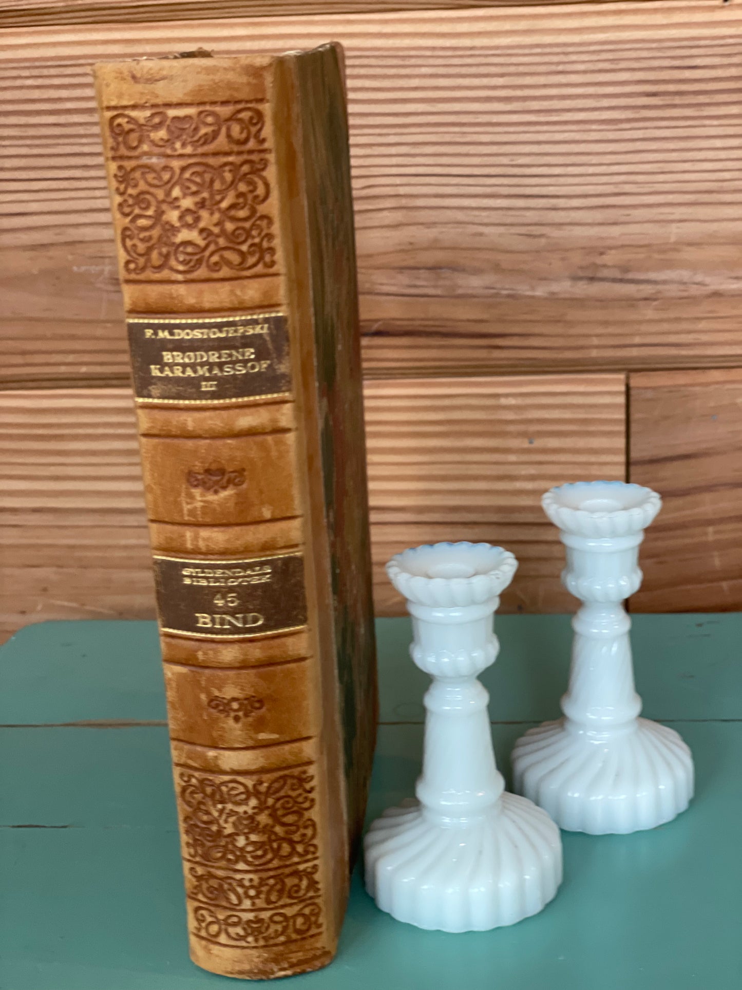 Vintage White Opaline Candlesticks - 3.5-inch set of 2 beside an antique book, adding a timeless and elegant charm to any home decor setting.