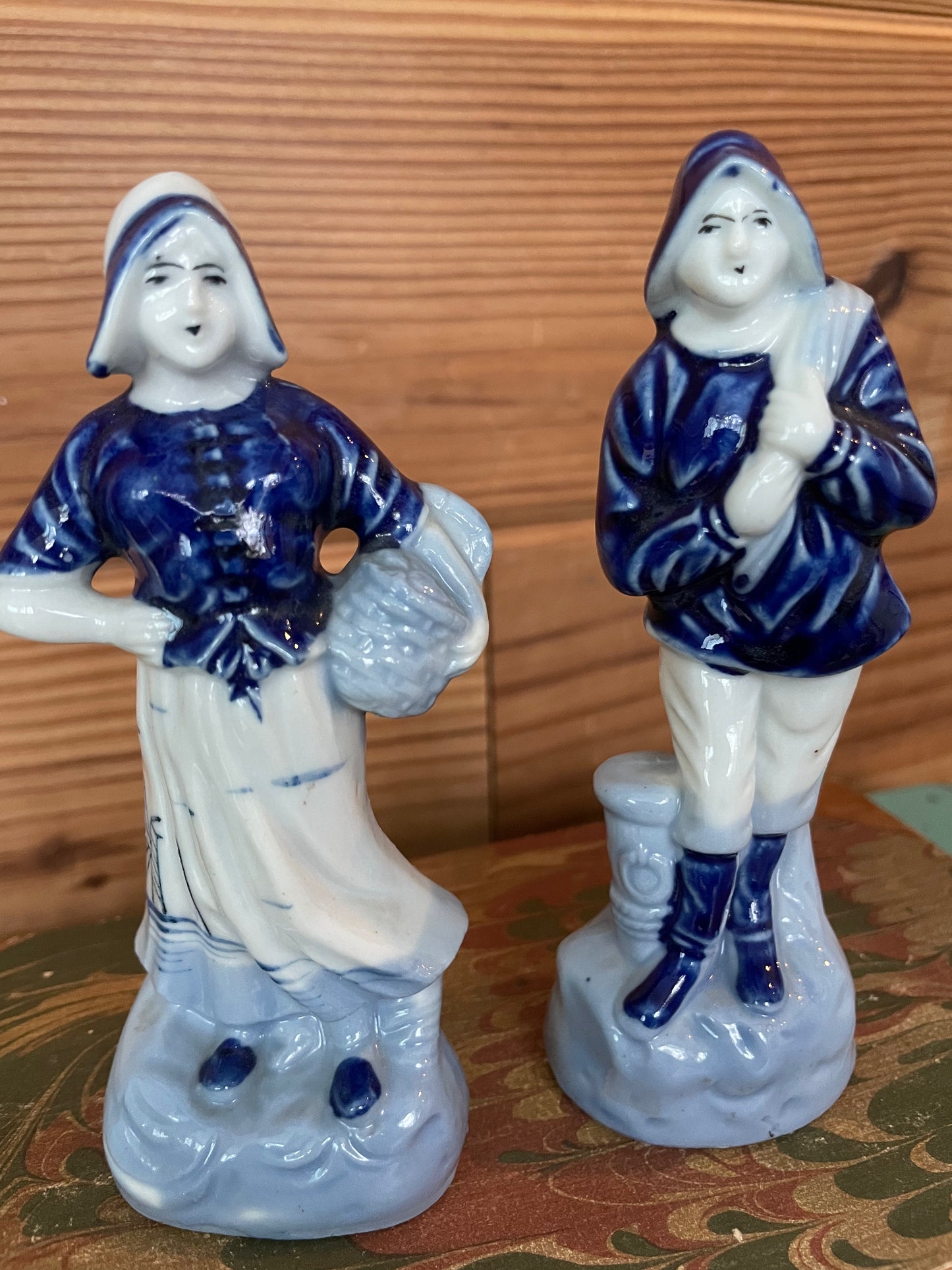 Close-up of vintage Blue Delft porcelain figurines, showcasing intricate hand-painted details of a Dutch woman and fisherman in traditional attire.