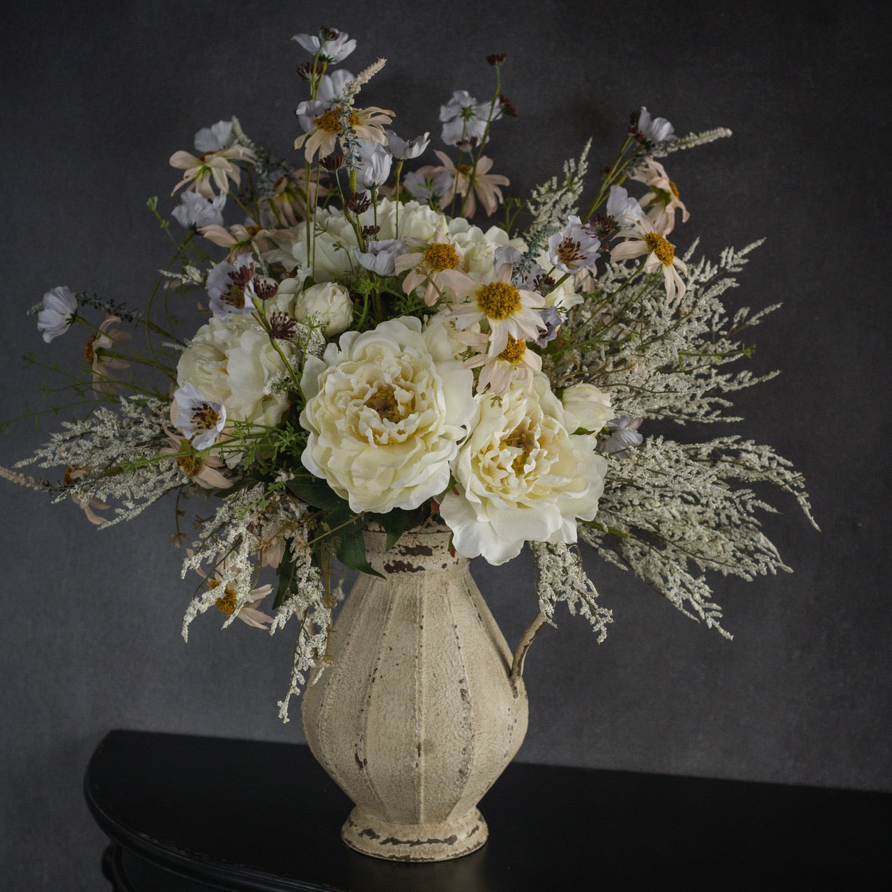 Luxurious floral arrangement featuring Cream Peony Spray 15-inch with wildflowers in a distressed vase. Perfect for elegant home and event decor.