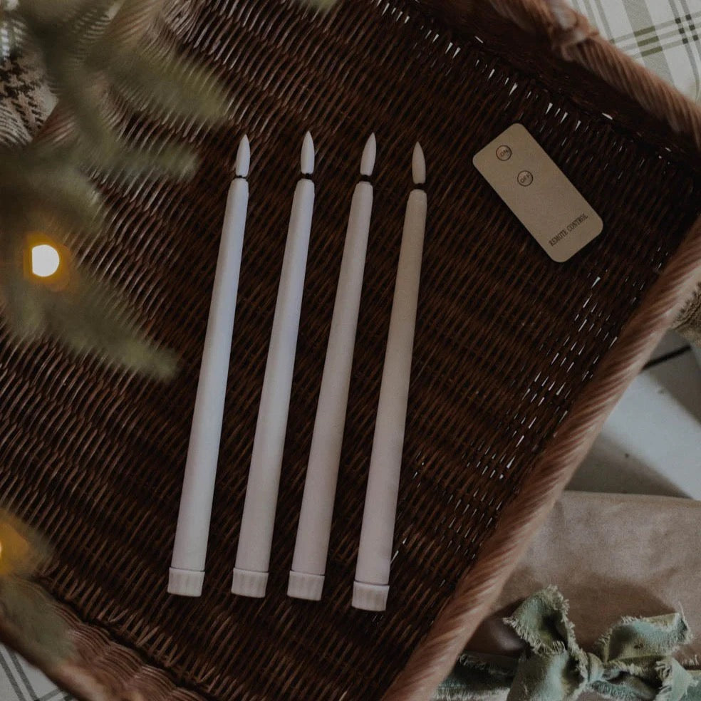 Battery-operated flameless taper candle set by Antique Candle Co., featuring a remote control for easy use, displayed in a woven basket.