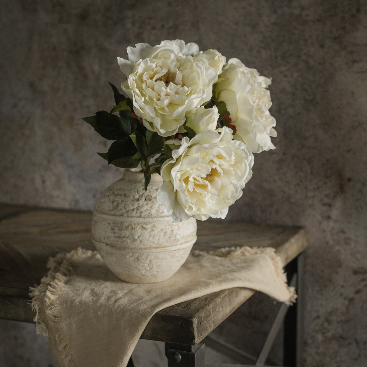 Cream Peony Spray 15-inch arranged in a vintage ceramic vase on a rustic table. Adds timeless beauty to floral arrangements and home decor.