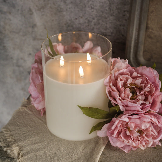 Glass 3 wick candle with 3D flame effect, surrounded by pink flowers. Elegant home decor piece for a warm, realistic ambiance.