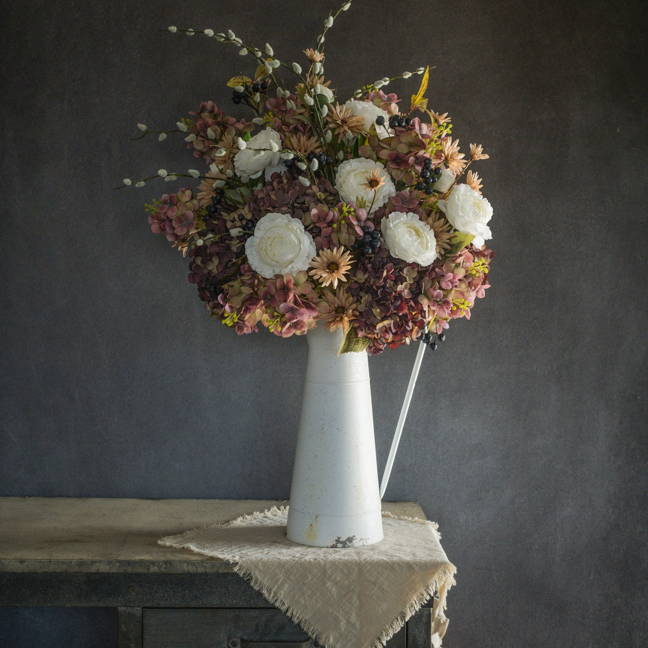 White peony spray mixed with dried flowers in a vintage white pitcher, creating a charming, rustic floral centerpiece for home decor.