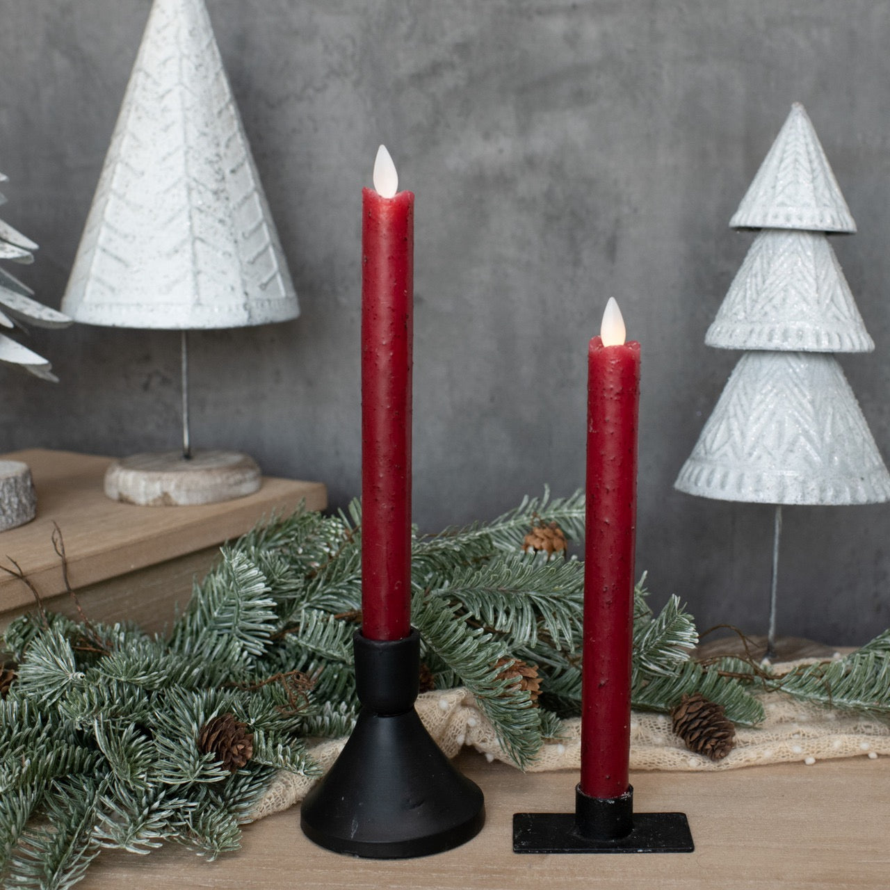 Elegant 9.5-inch moving flame red taper candles in festive decor with winter greenery and white Christmas trees. Ideal for holiday and home ambiance.