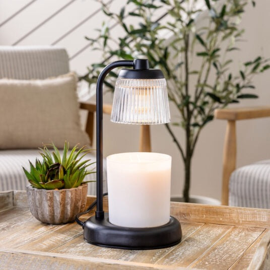 Fluted Glass Black Candle Warmer Lamp elegantly placed on a wooden table in a cozy living space, providing a warm and inviting ambiance.