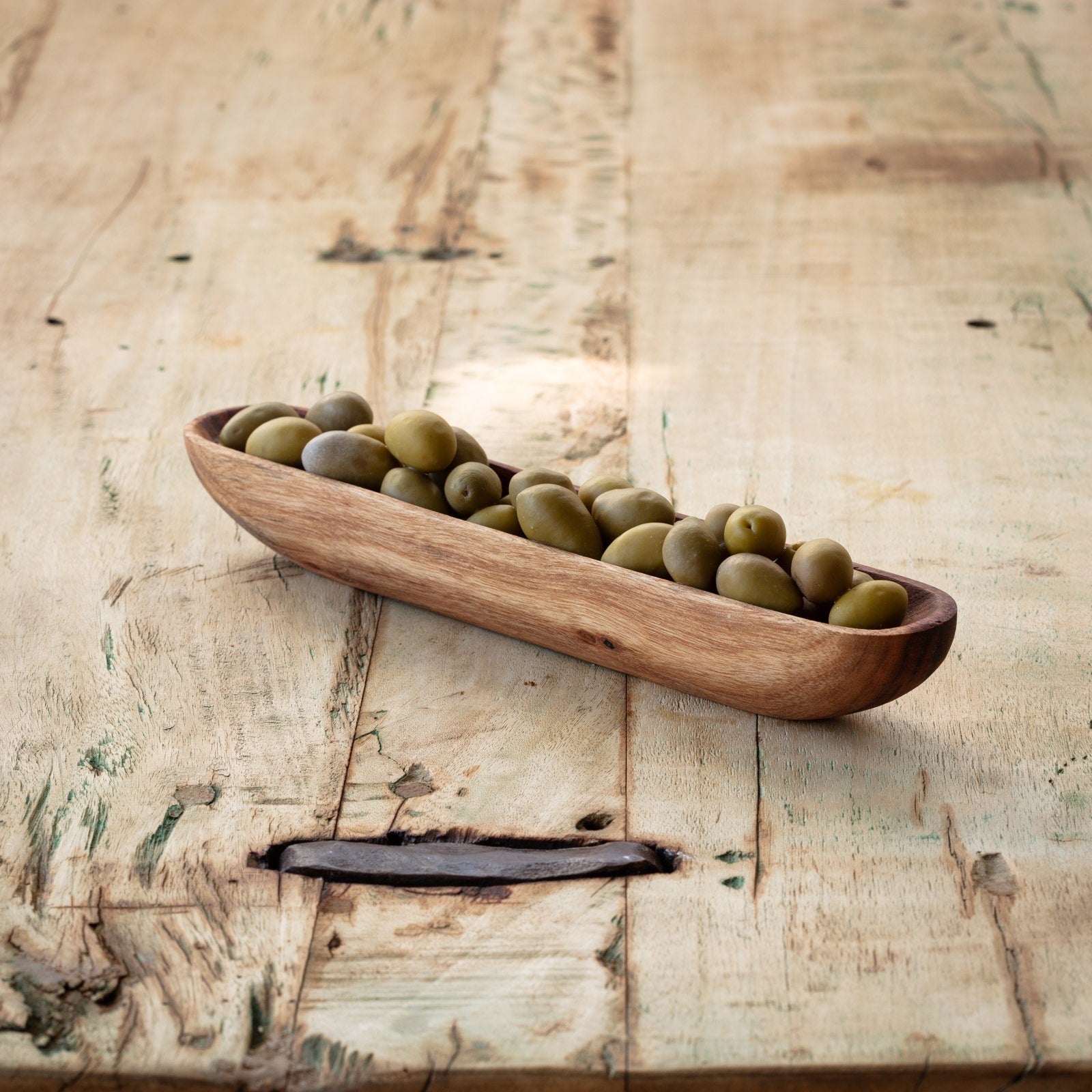 Wooden olive tray filled with green olives, ideal for serving alongside meats and cheeses. A stylish addition to any charcuterie spread.
