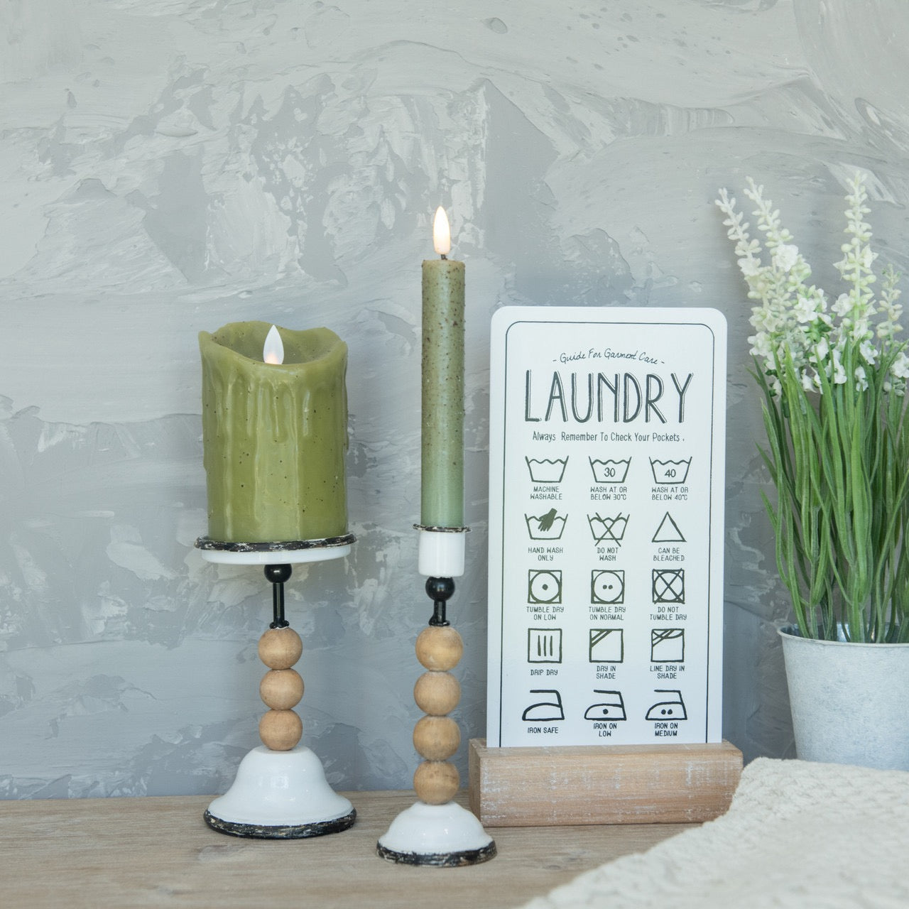 Rustic combination taper and pillar candle holders in use, featuring green candles and a vintage laundry sign, enhancing farmhouse-style decor.