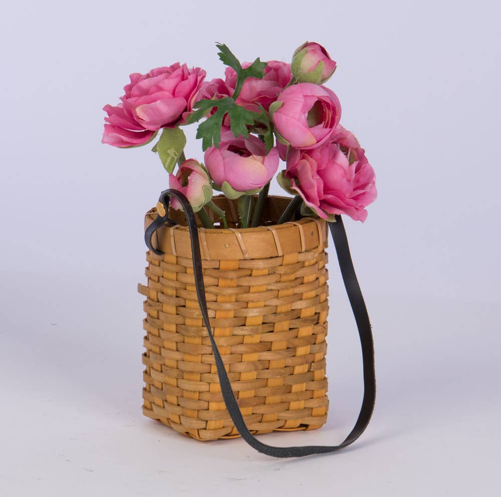 Oval Chipwood Hanging Planter filled with pink flowers. Woven basket with a leather strap, ideal for seasonal floral arrangements and decor.