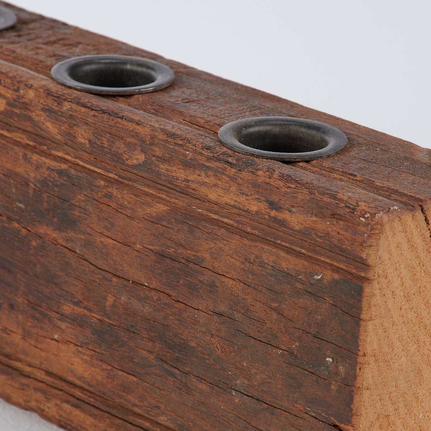 Close-up of Primitive Wood Candle Holder with four metal slots. Aged wooden texture enhances its antique-style charm.