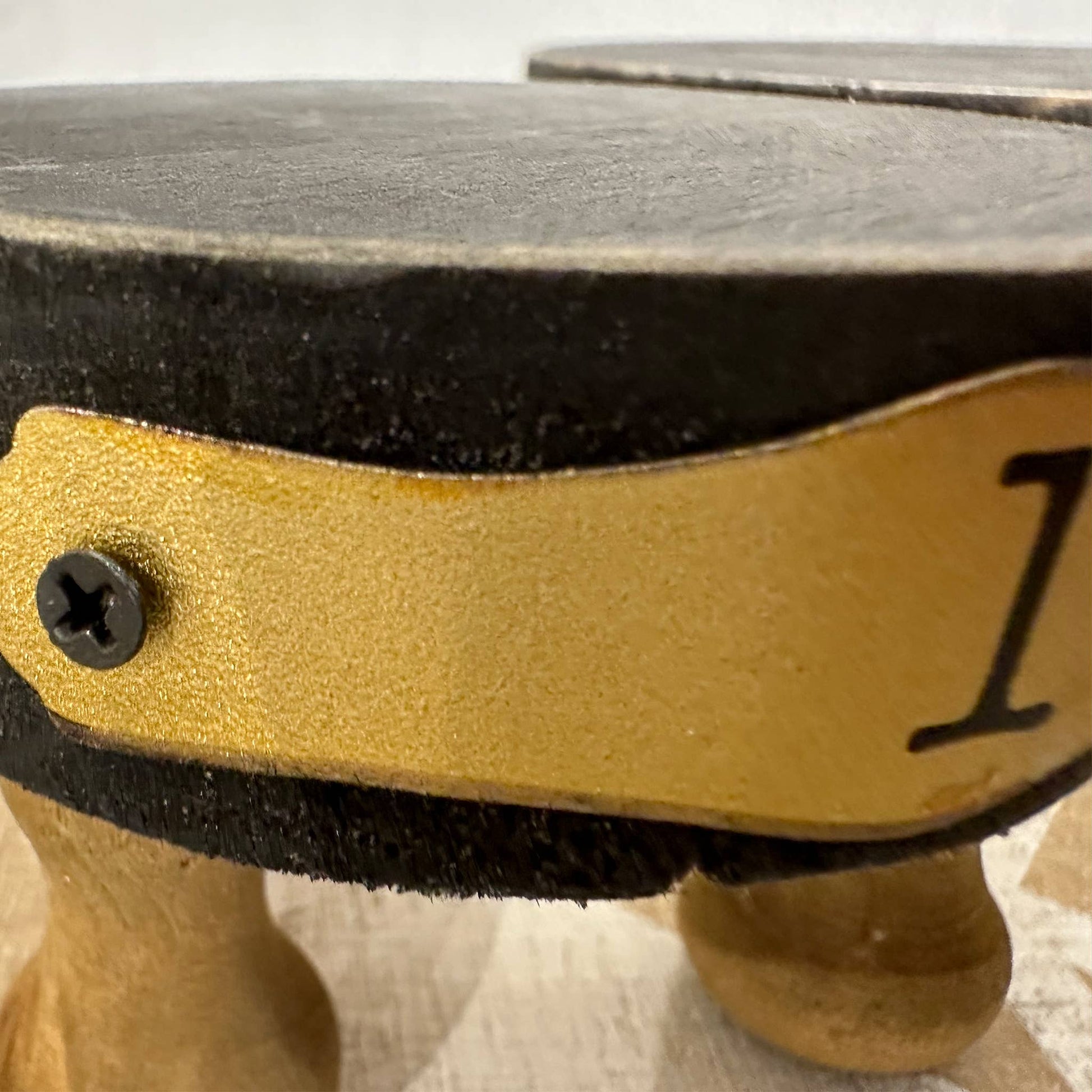 Close-up of a black wooden display riser with gold trim and wooden legs. Sturdy and stylish, ideal for showcasing decor, candles, or plants.