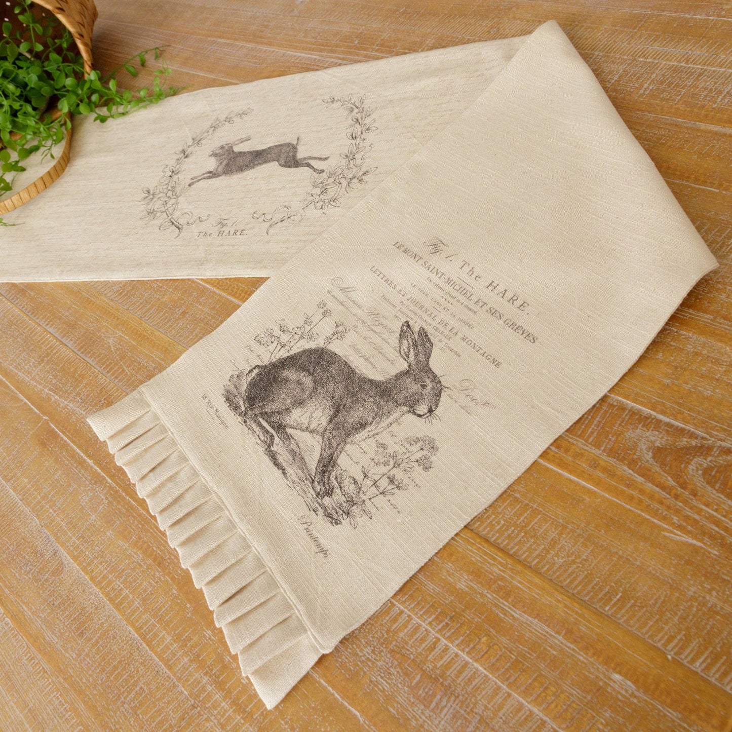 Cotton table runner with a reversible design, featuring a detailed hare illustration and French script. Adds a rustic charm to Easter or spring tablescapes.