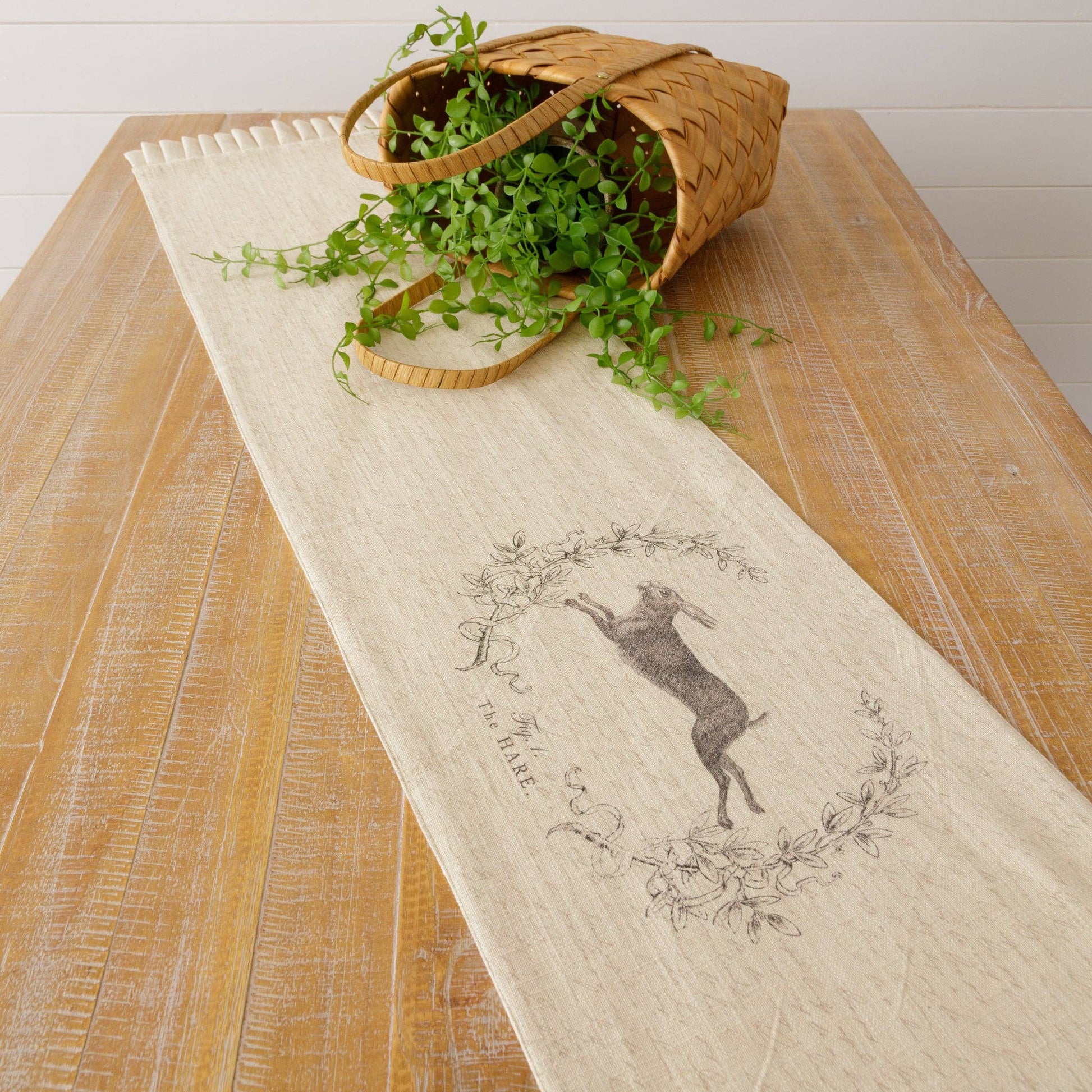 Elegant French hare table runner with a reversible design, showcasing a leaping rabbit within a botanical wreath. Ideal for Easter or seasonal gatherings.