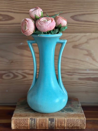 Vintage USA pottery vase in turquoise with a classic mid-century design, featuring elegant curved handles. Displayed with pink flowers on antique books.