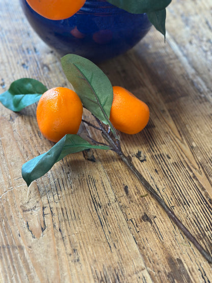 Single artificial orange floral pick with green leaves on a rustic wooden surface. Great for DIY crafts and home decor arrangements.