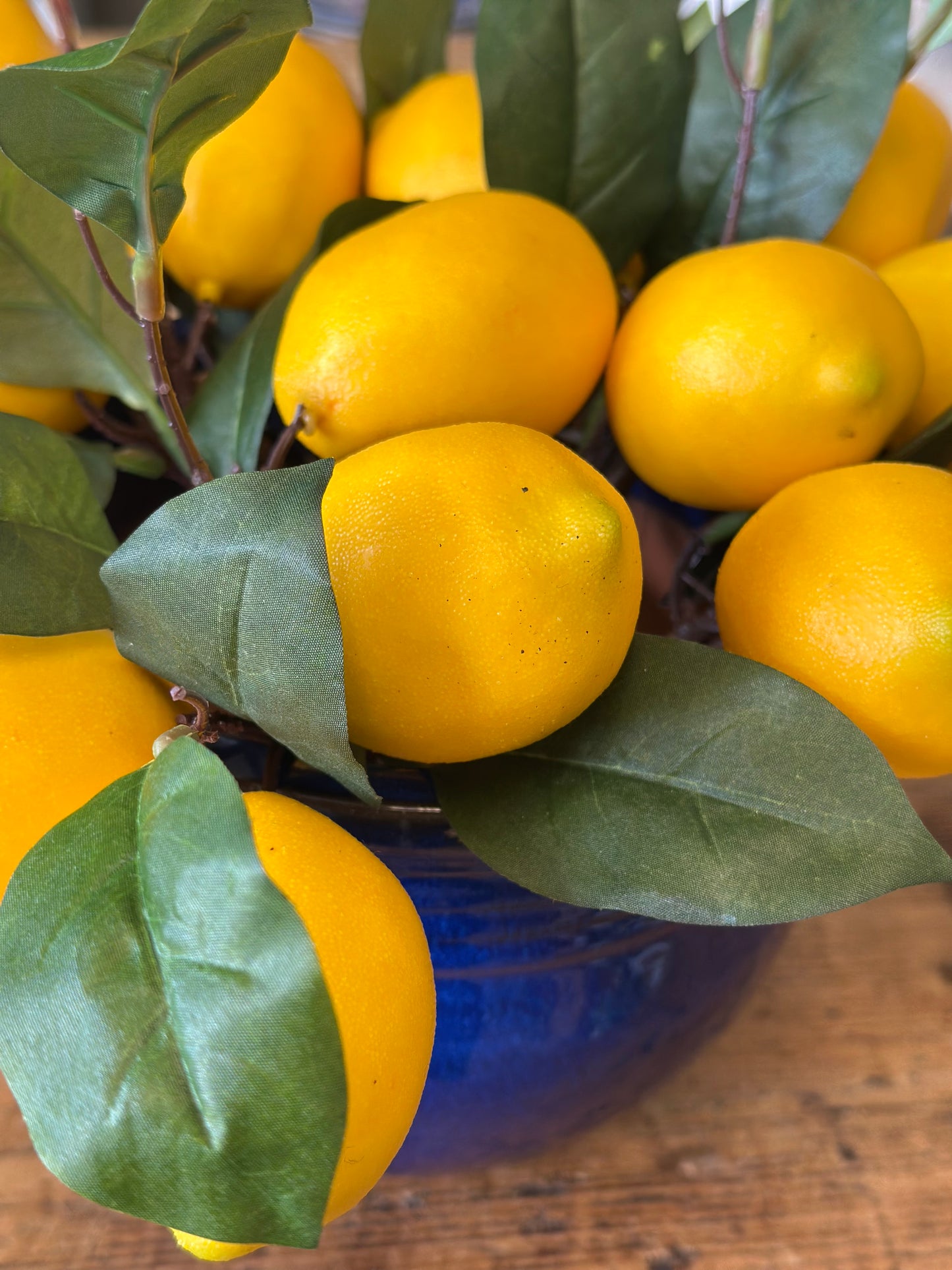 Bright lemon floral picks arranged in a blue pot with lush green leaves. Perfect for refreshing floral decor and creative arts & crafts projects.