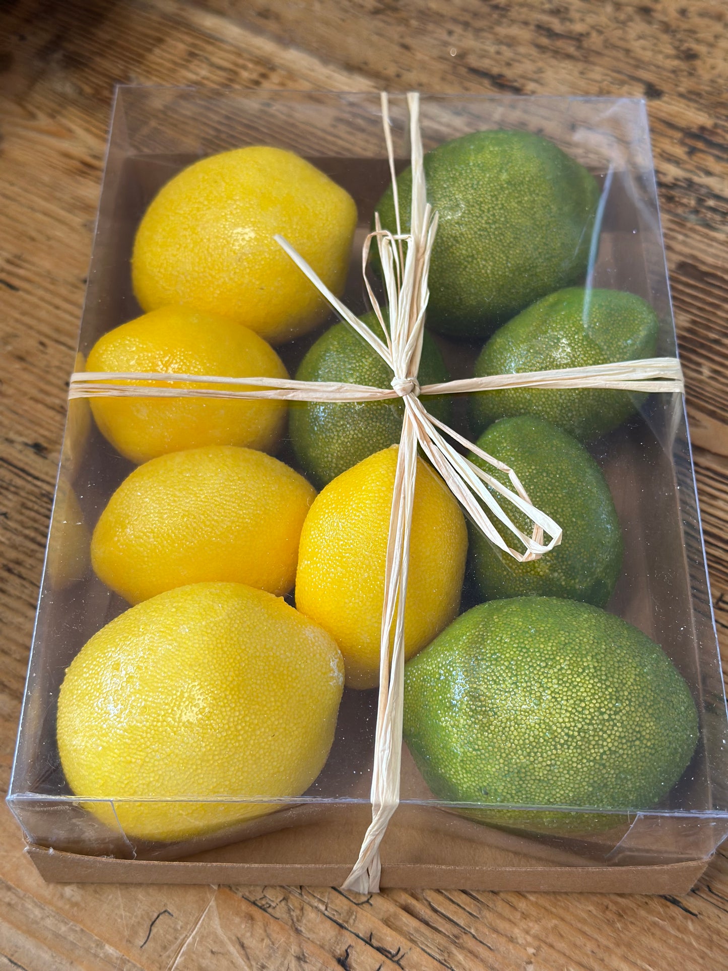 Faux lemon and lime decor pack featuring 10 realistic artificial citrus fruits in a clear gift box with a raffia ribbon. Perfect for home decor and displays.