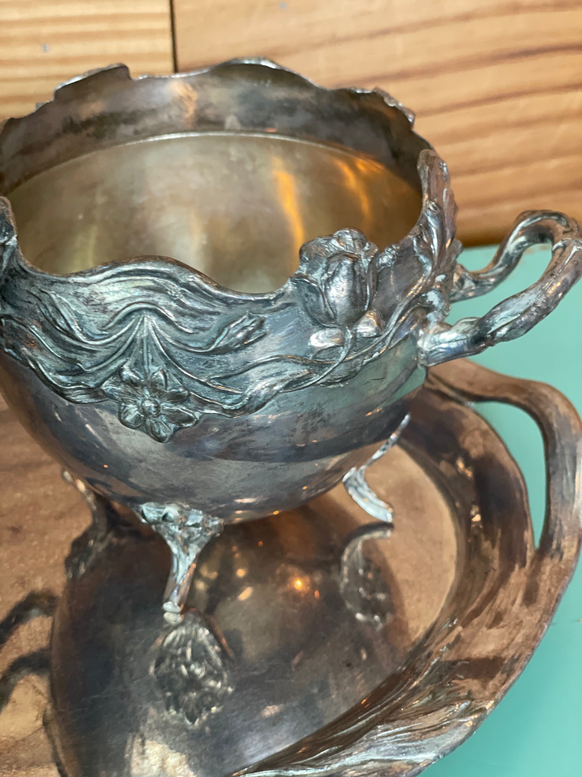 Detailed view of vintage silver-plated sugar bowl with ornate floral patterns and curved handles. A charming addition to any refined tea or coffee service.