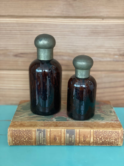 Vintage tortoise glass bottles set with brass lids, elegantly placed on an antique book. A perfect decorative accent for home decor enthusiasts.