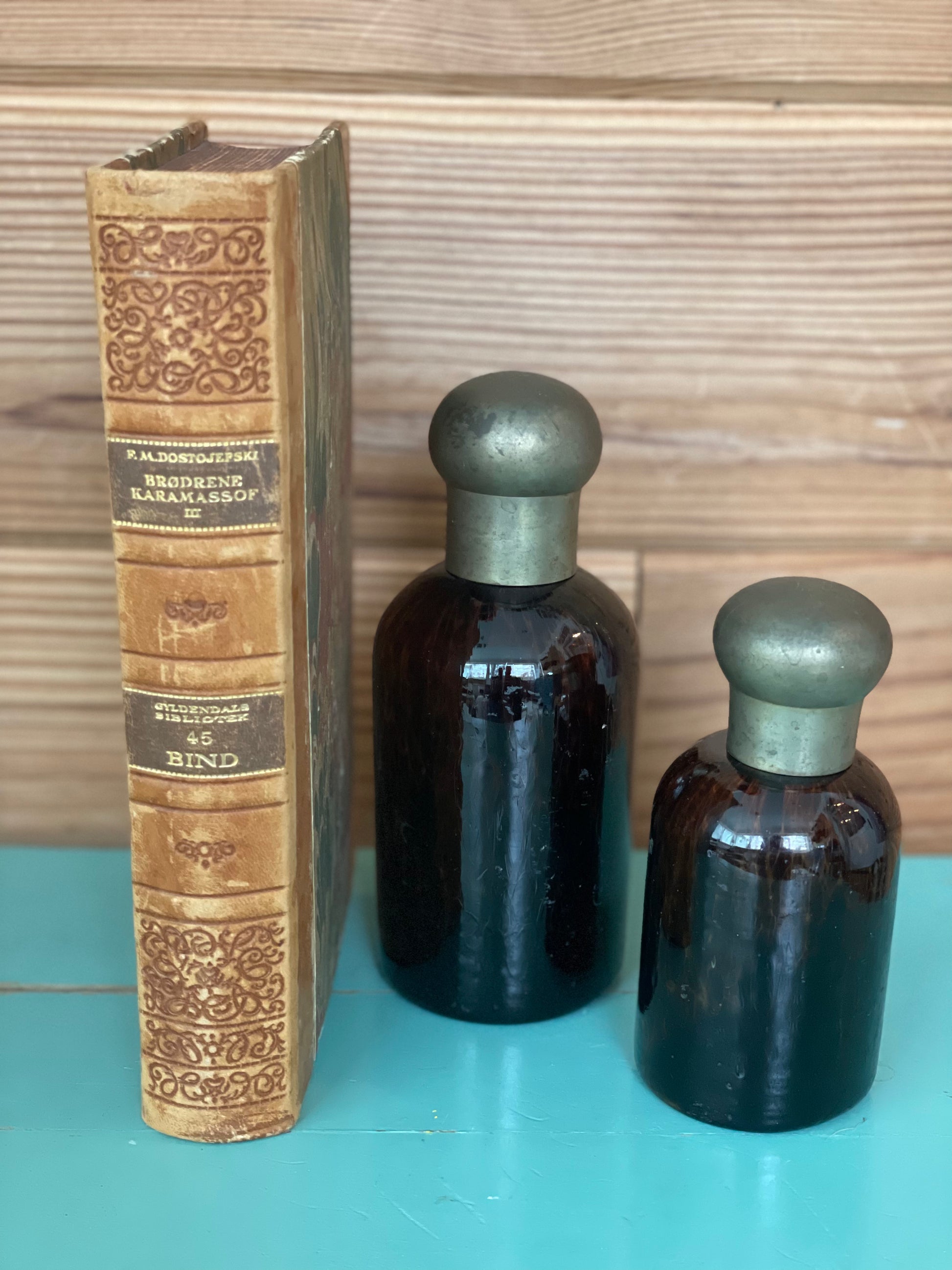 Vintage tortoise glass bottles with brass lids beside an antique book. A timeless decorative piece for collectors and home decor lovers.