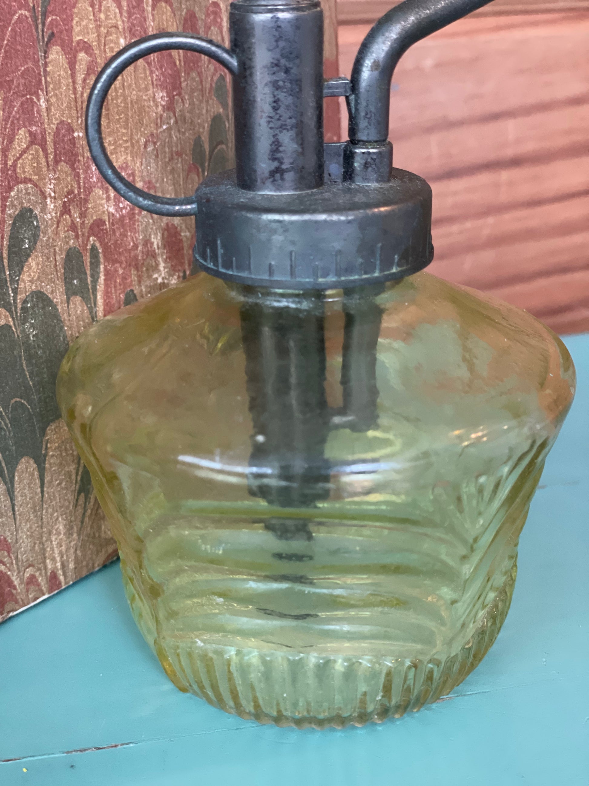 Close-up of a vintage green glass mister bottle featuring a textured design and black metal pump. Perfect for watering plants and adding a classic touch.