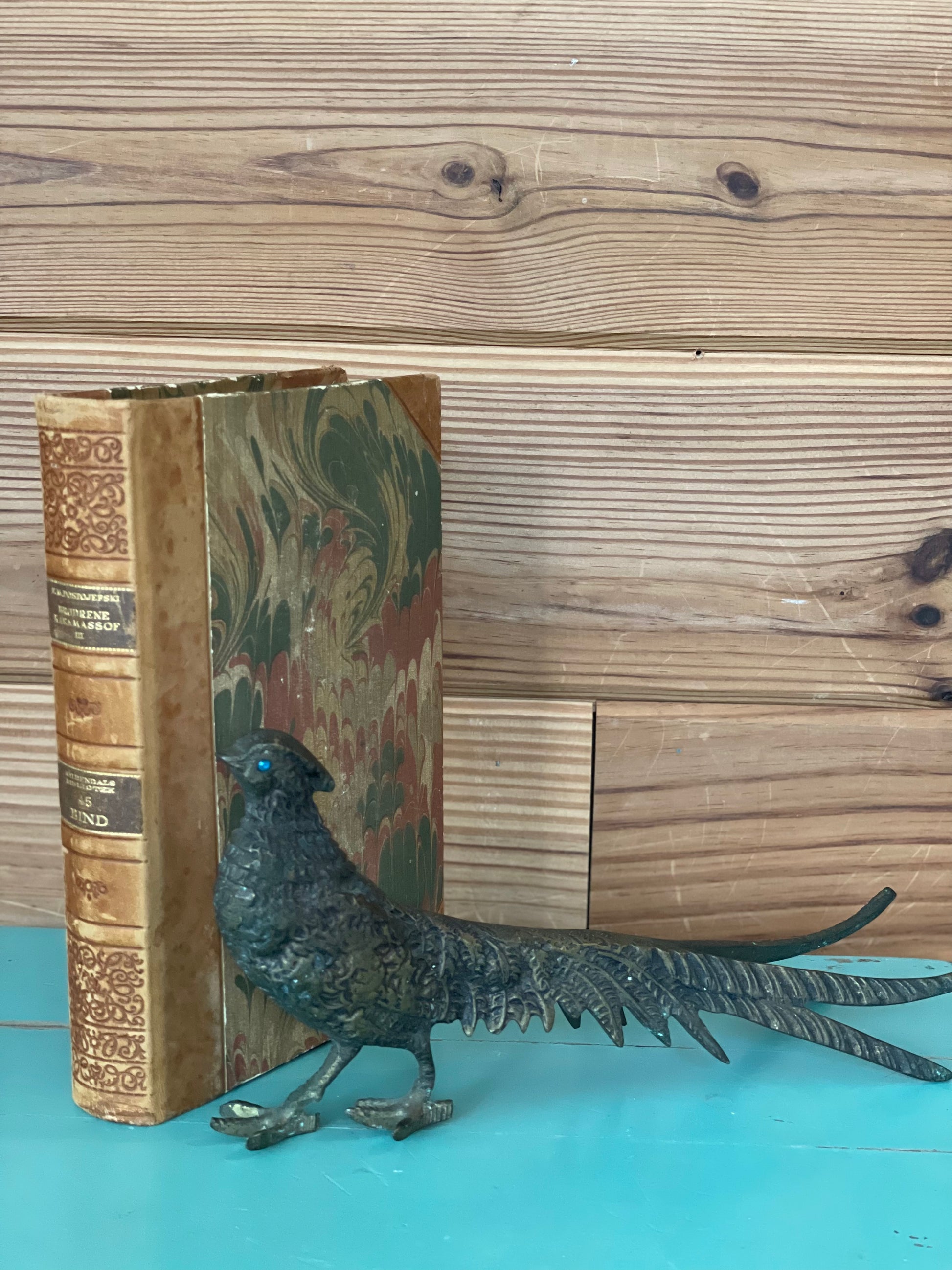 Vintage brass pheasant decor with intricate detailing, placed beside an antique book. A perfect elegant home decoration for shelves or mantels.