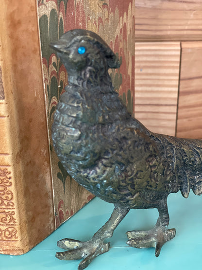 Close-up of a vintage brass pheasant sculpture showcasing fine craftsmanship and blue gemstone eyes. A sophisticated home decor accent.