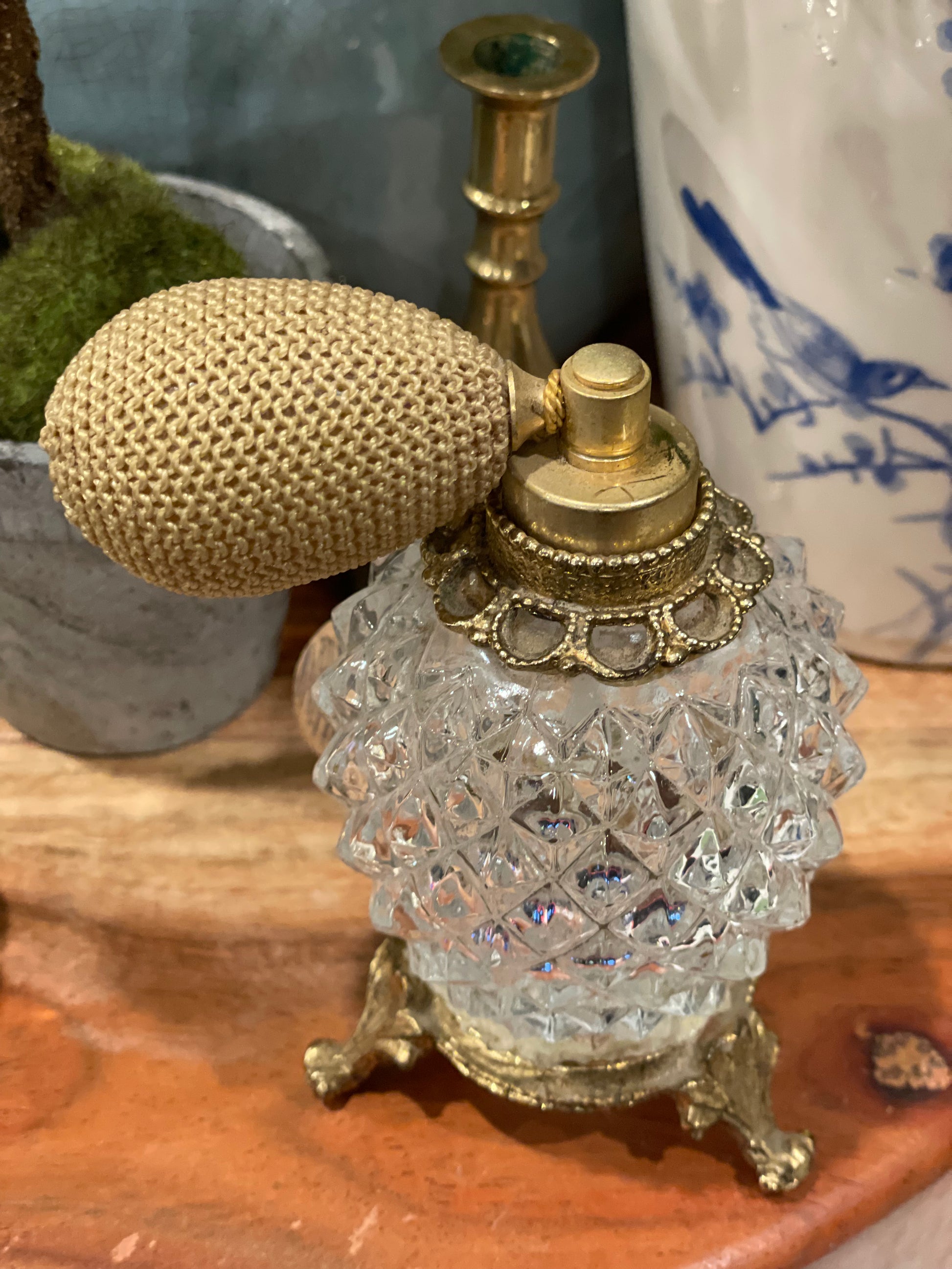 Close-up of vintage diamond point glass atomizer bottle with gold-tone pedestal and intricate detailing. Ideal for perfume or essential oils.