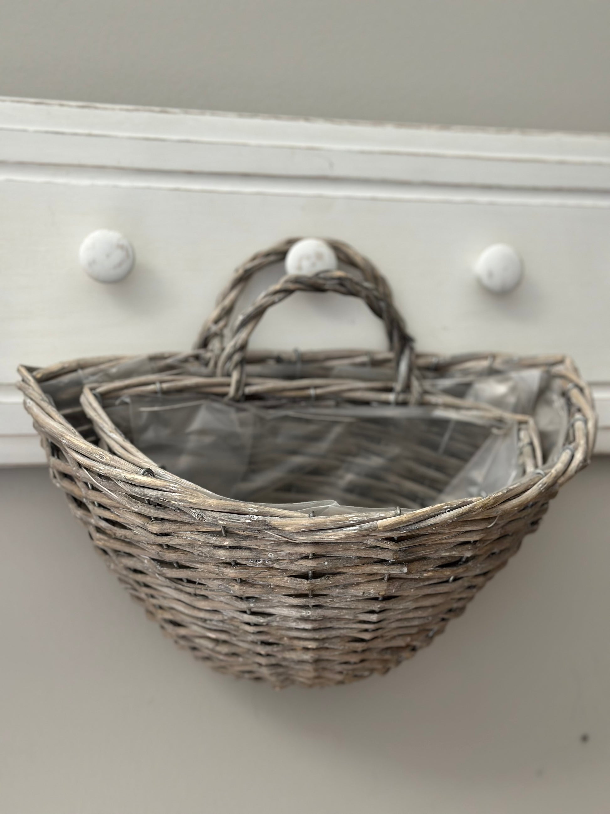 Close-up of nested gray wicker storage baskets with plastic lining. Perfect for home organization and decorative storage solutions.