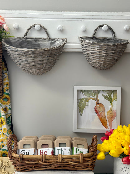 Set of two gray wicker storage baskets with handles, hanging on white hooks. Stylish and durable for home decor, ideal for organizing accessories or flowers.