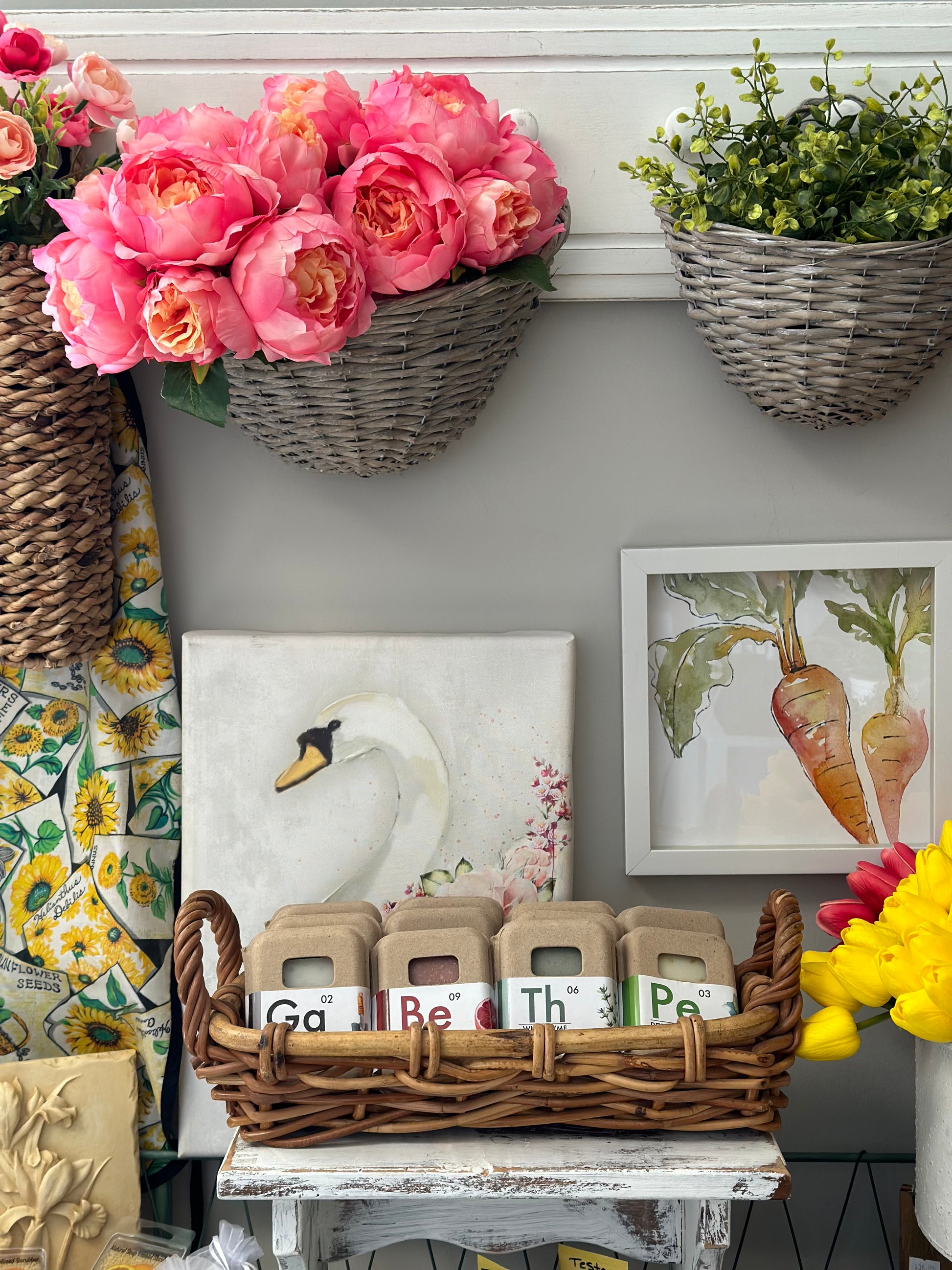 Gray wicker storage baskets filled with pink flowers and greenery, enhancing a cozy home decor setup. Ideal for stylish organization and display.