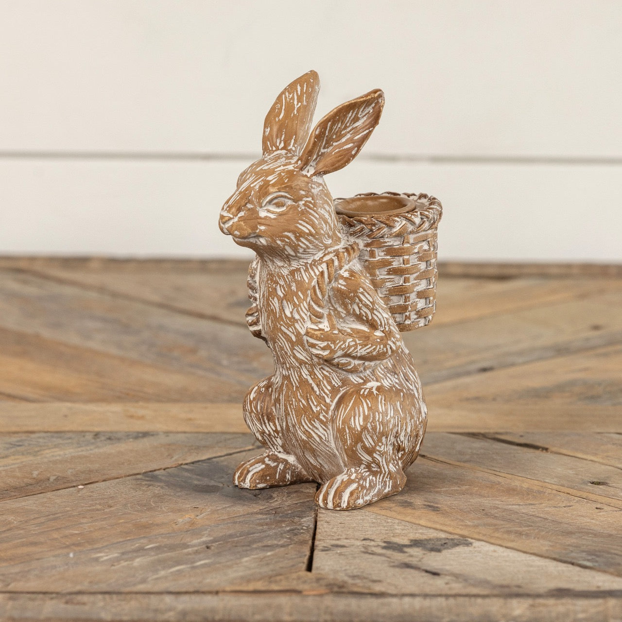 Bunny taper candle holder with a rustic finish, featuring a rabbit carrying a woven basket. Perfect for Easter and farmhouse-style decor.