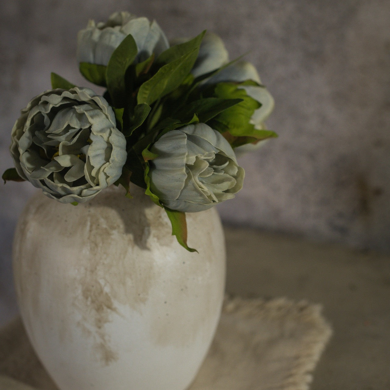 Artificial Dusty Blue Peony Bundle in a rustic white vase against a moody backdrop. A timeless floral accent for sophisticated home decor.