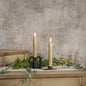 Set of 2 gold taper candles with realistic 3D flame, placed on a rustic wooden surface with greenery. Elegant home decor for a warm ambiance.