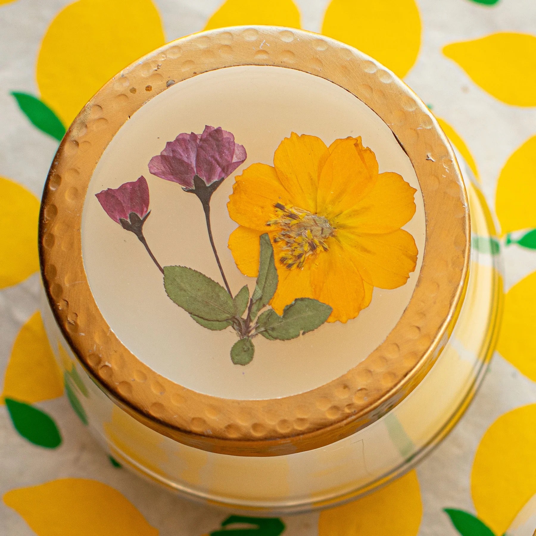 Rosy Rings Lemon Blossom floral candle with a decorative lid featuring pressed yellow and pink flowers. Handmade with a coconut wax blend for a 70-hour burn time.