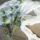 Elegant Blue Berry Foliage Spray displayed on soft white fabric, showcasing its lifelike berries and lush green leaves for decor styling.