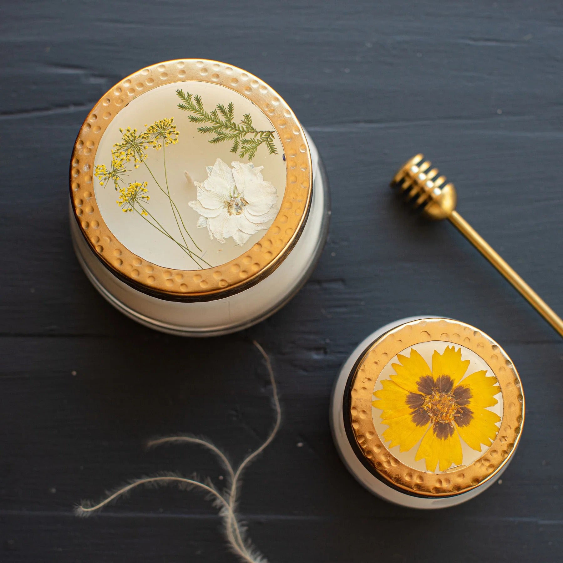 Rosy Rings Honey Tobacco floral scented candles in two sizes with decorative gold lids featuring pressed flowers. Elegant home decor with a 70-hour burn time.