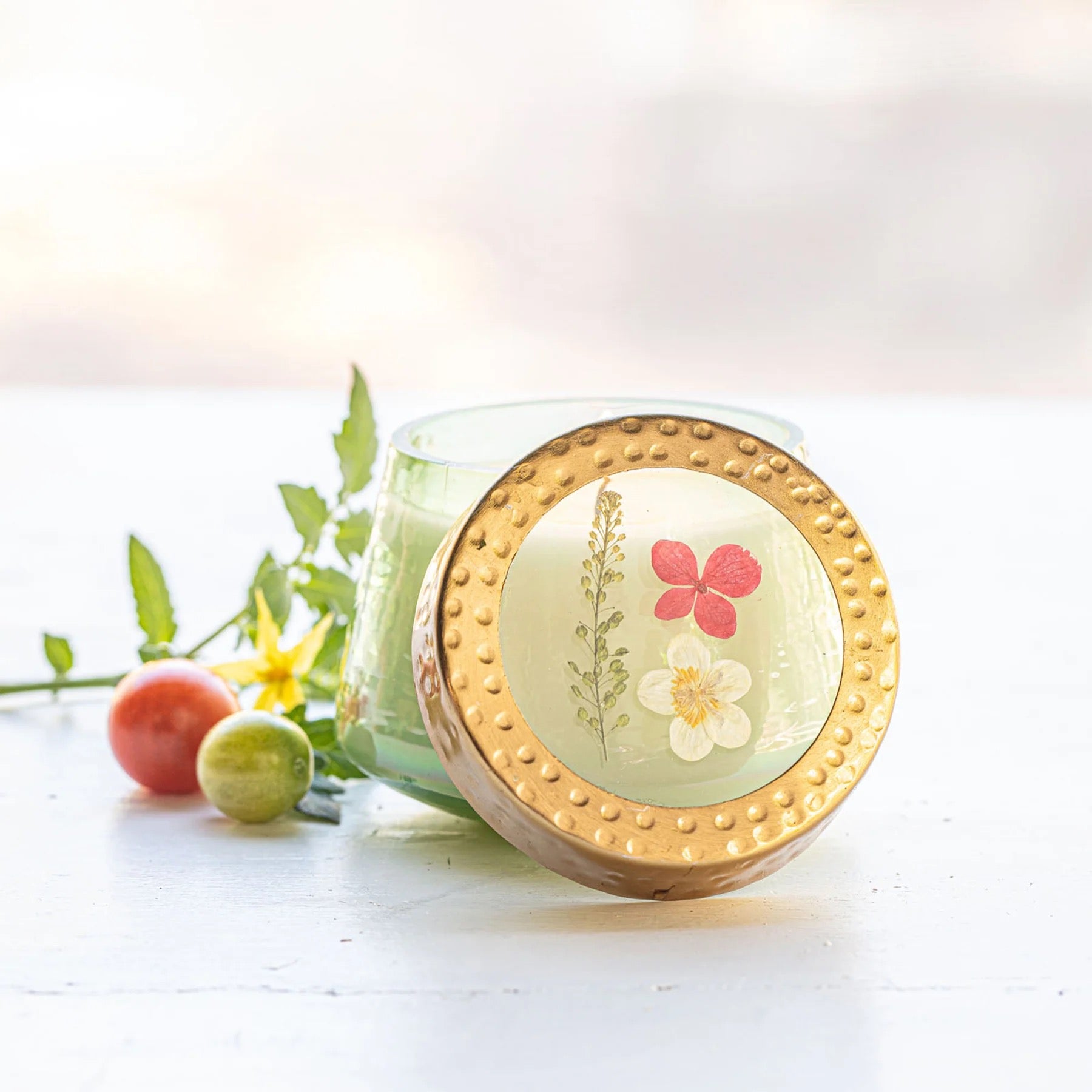 Rosy Rings Tomato Vine Candle in a green glass jar with a floral-embedded lid. Features a fresh botanical scent and a 35-hour burn time.