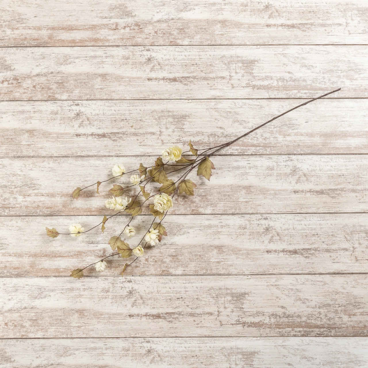 Single 39-inch Cream Hops Stem laid on a rustic wooden surface, showcasing its delicate artificial floral design for decor enhancement.