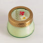 Rosy Rings Tomato Vine Candle with floral-embedded glass lid and gold rim. Hand-poured coconut wax blend in a green glass jar for a 35-hour burn.