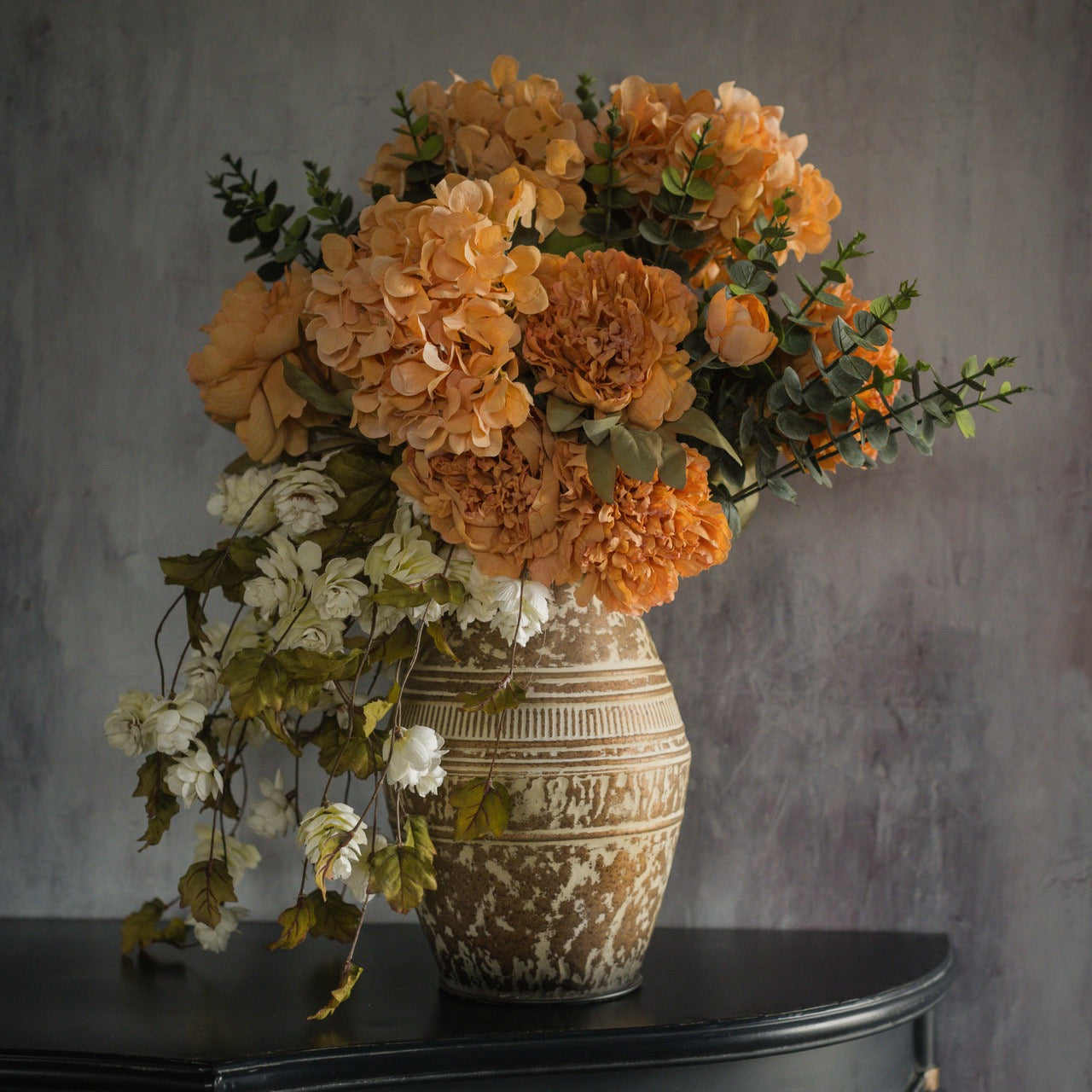 Cream Hops Stem combined with vibrant orange artificial flowers in a rustic vase, enhancing floral arrangements with texture and elegance.